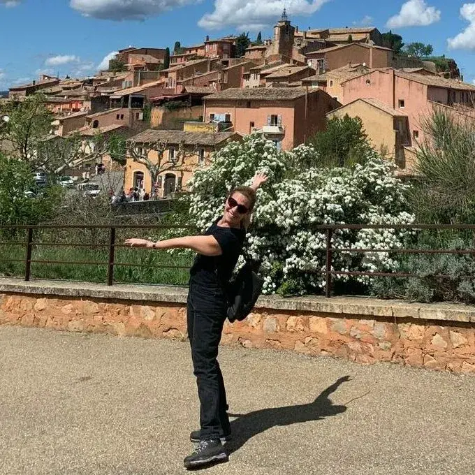 Maria Thedim, traductrice et guide pour séjours linguistiques et culturels en Provence, posant devant un village perché.